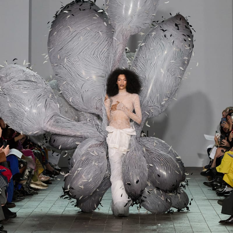 Fashion catwalk model surrounded by large grey cactus-like balloons