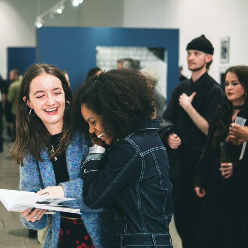 Two young women affectionate and laughing in an exhibition