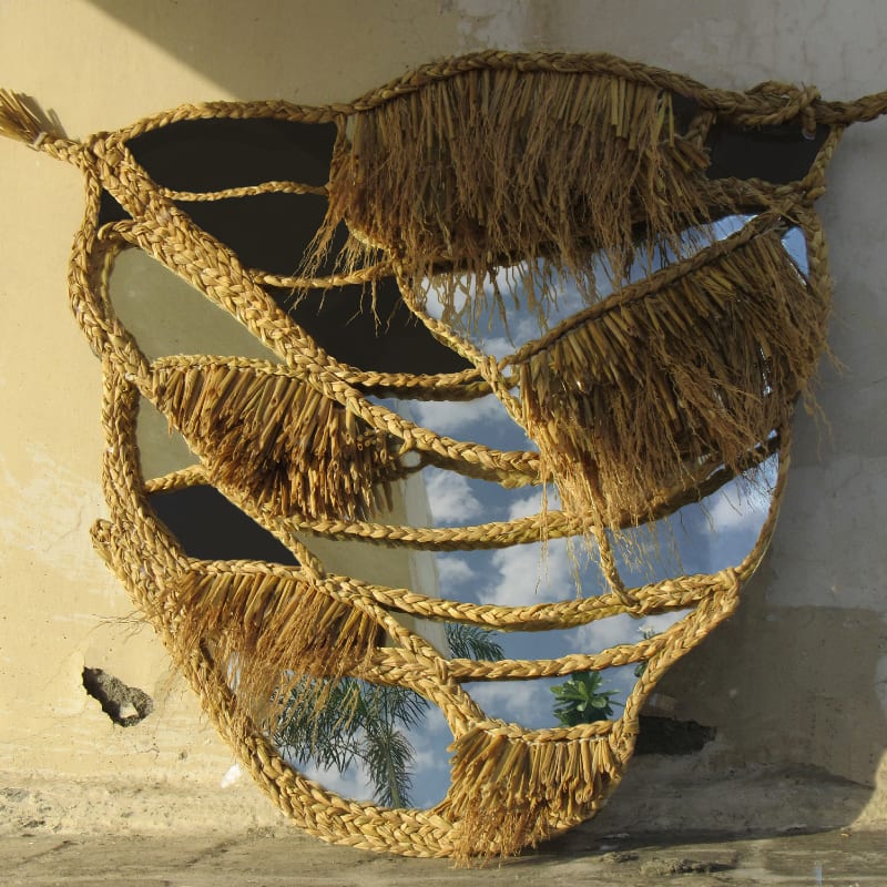A textiles sculpture which is crafted in a light brown woven fabric with a mirror installed into the sculpture.