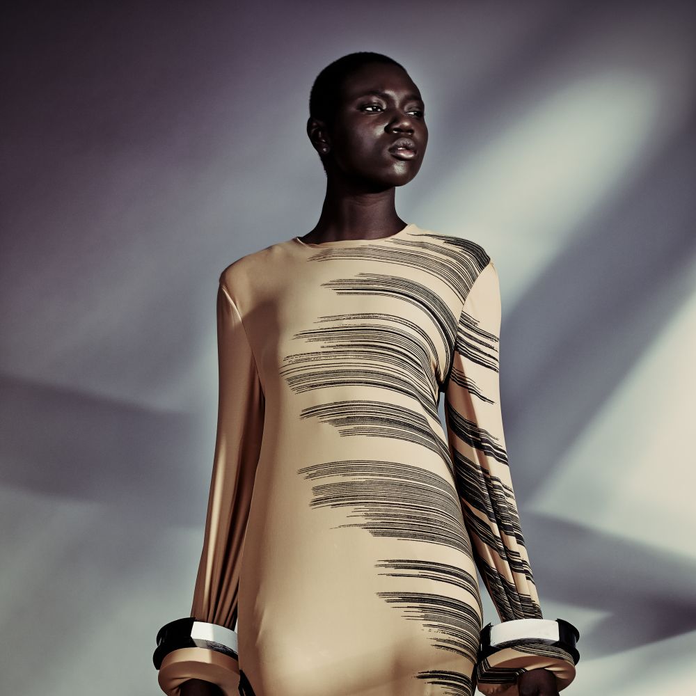 Black woman in gold dress and jewellery.
