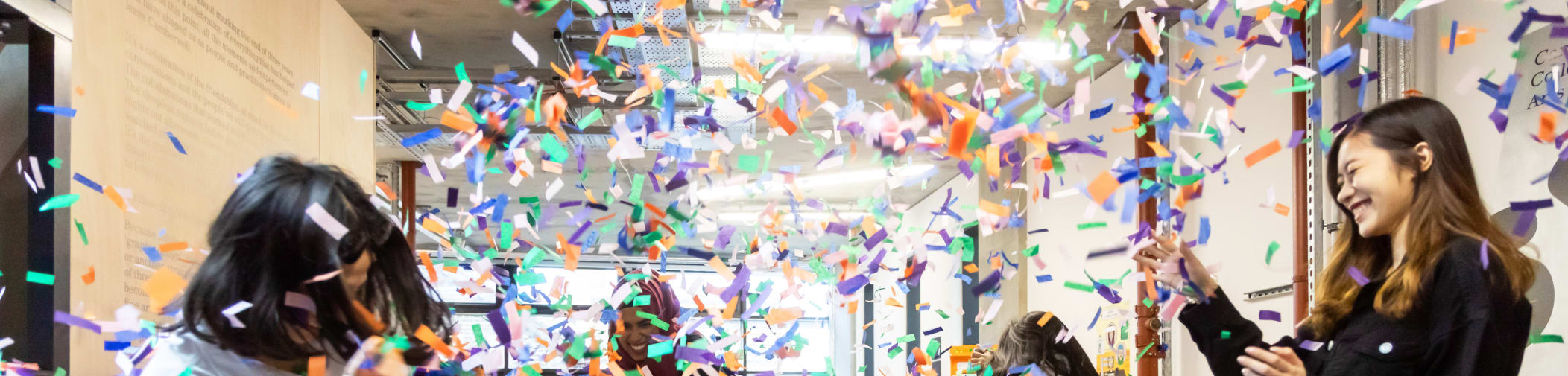 Degree show attendees throwing confetti in the air