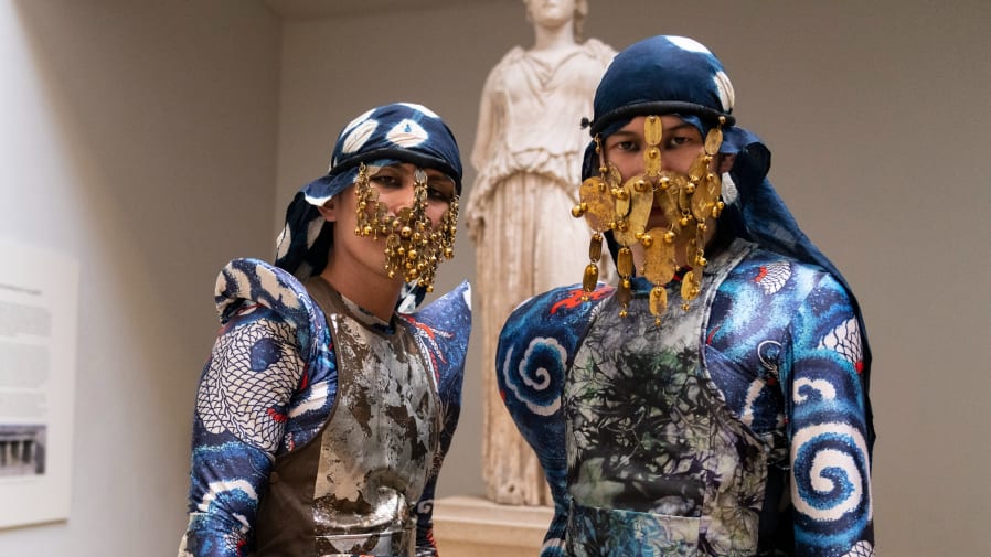 Warriors with intricate gold masks, eye makeup and blue costumes