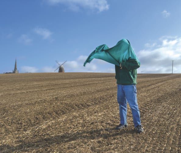 A person in a field waving a green cloth