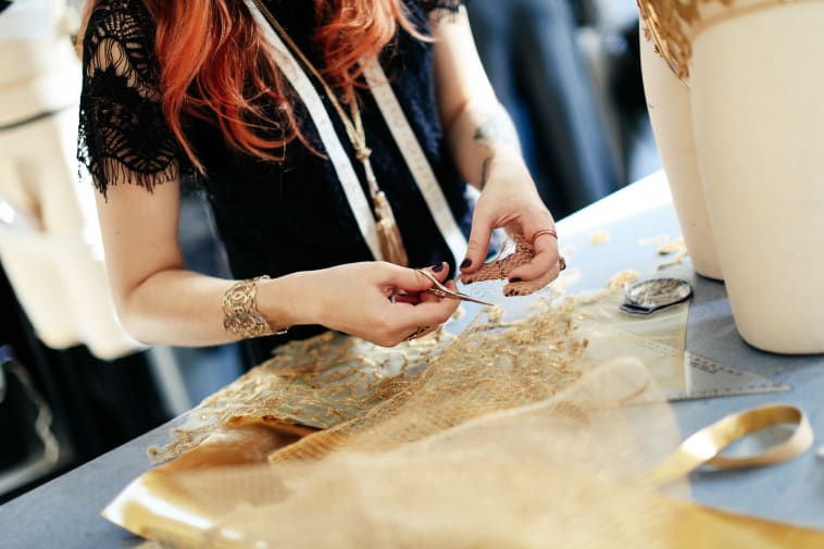 Close up shot of a student cutting some gold netted material.