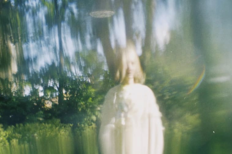 A blurred image of a model in an area of woodland
