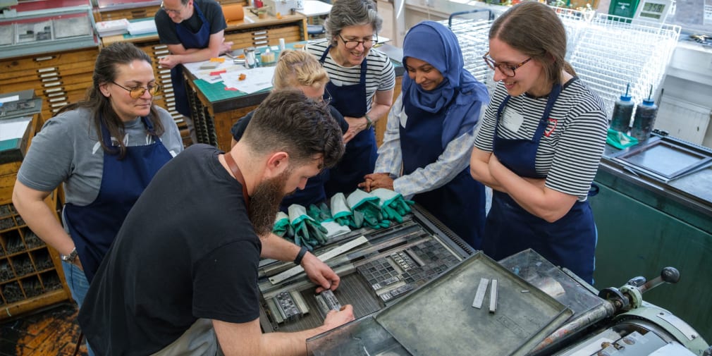A print technician demonstrates how to lay out set letters in the print studio