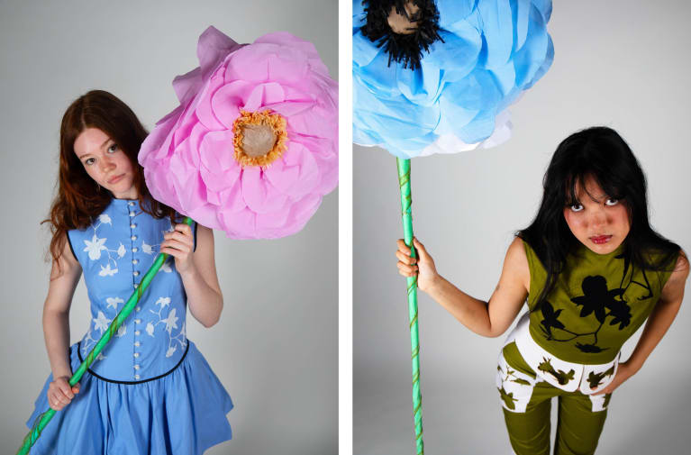 Young female models in fitted dress / jumpsuit with oversized paper flowers.
