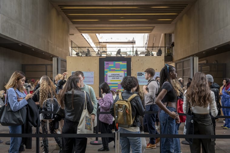 A line of people wait at the Creative Opportunities job fair registration desk