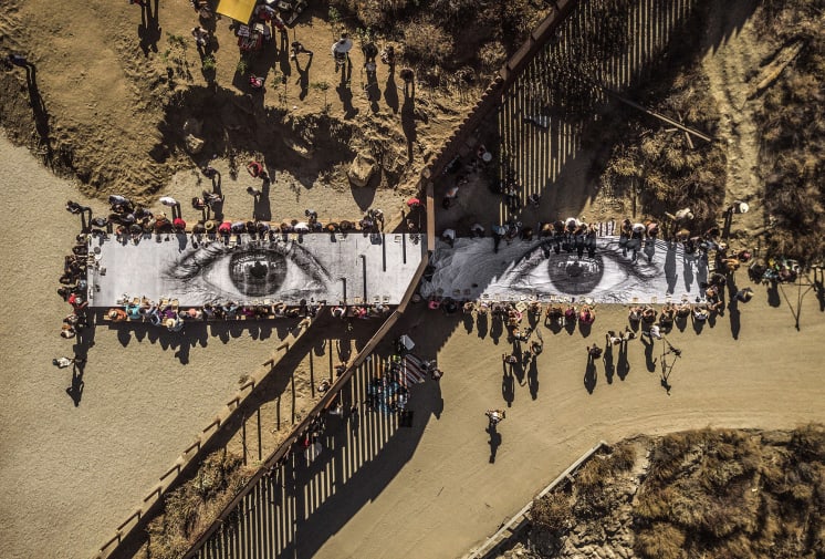 JR (French, born 1983). Migrants, Mayra, Picnic across the Border, Tecate, Mexico - U.S.A, 2017. Installation image. Wheat-pasted poster on table. Copyright: JR.