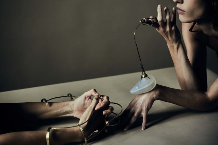 Models leaning in to each other wearing hand artefacts.