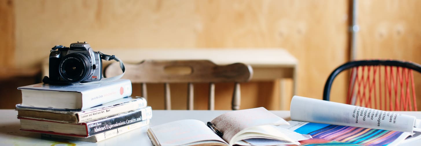 Image of a camera and a pile of books on a desk