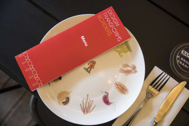 A large wall panel with a map of the world and red thread and the words 'Design Transforms Borders' and 'Where is home' and 'Territorial Empathy'