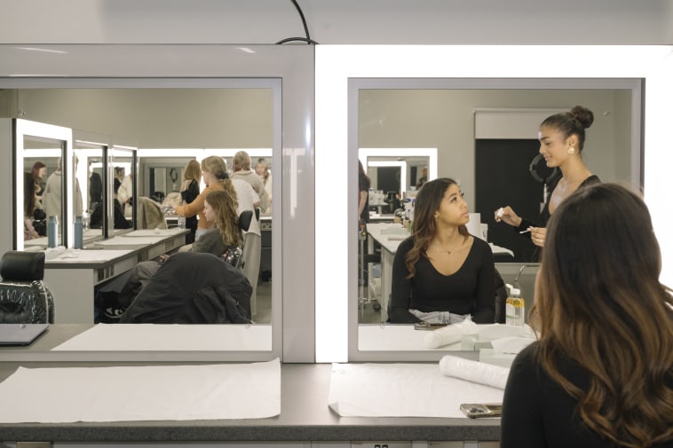 People in a room with bright lights and mirrors.