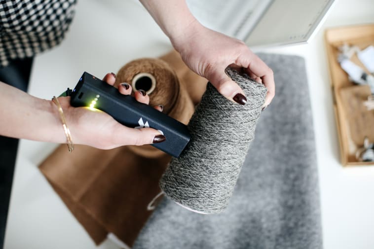 A photo of someone scanning a reel of yarn to trace what fibre it is made from. 