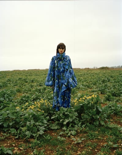 A girl in a blue dress standing in a field.