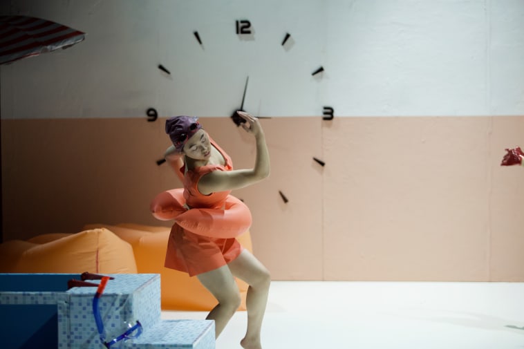 Figure in swimming clothes suspended mid fall in front of a clock