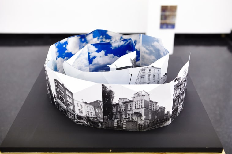 Black and white photographs of a city folded into a spiral, with images of the sky 