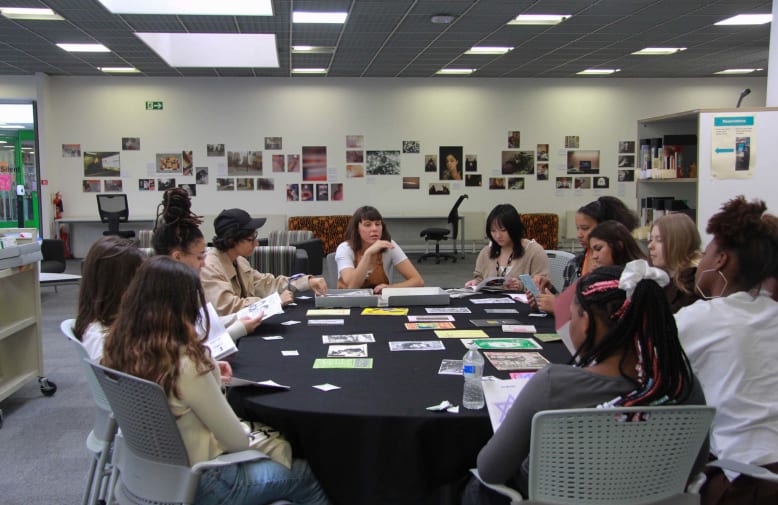 Students and a tutor sitting around a table with multiple images on it