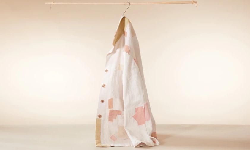 A single cream jacket hanging in the centre of the photograph. It has patches which are pink and beige