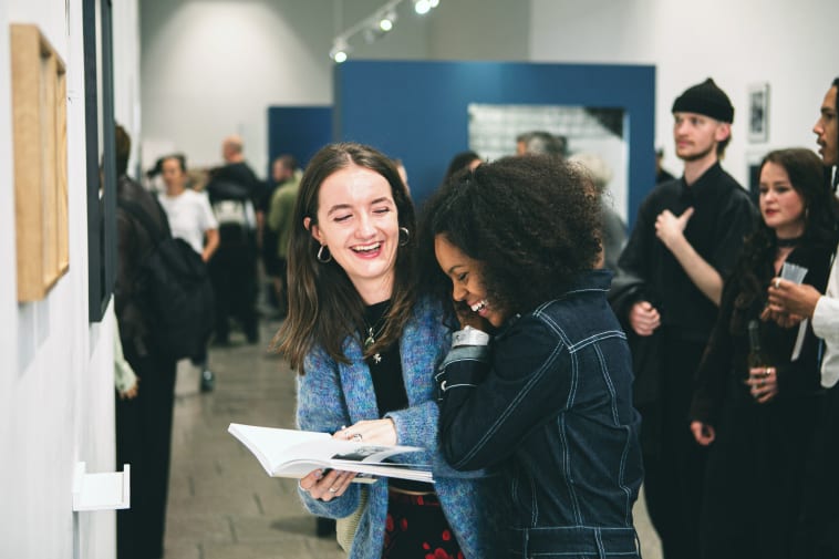 Two young women affectionate and laughing in an exhibition