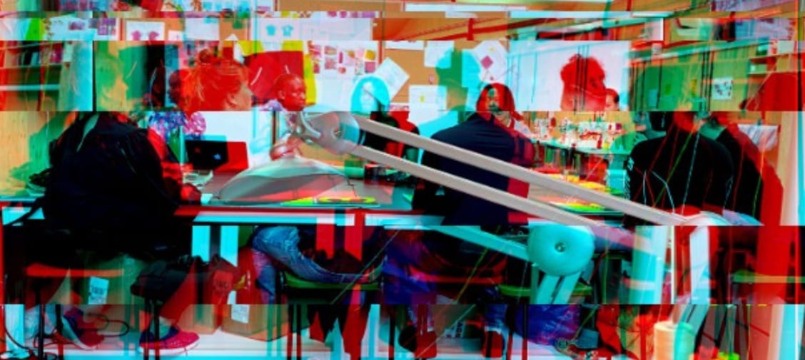 Students working around a table, glitched red and green image