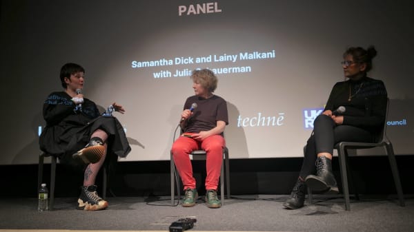 Samantha-Dick,-Julia-Schauerman-and-Lainy-Malkani-sit-on-stage-doing-a-panel-talk.jpg