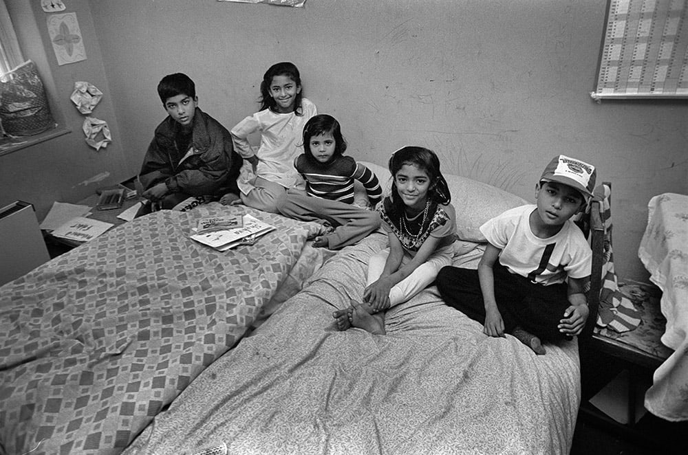 Black and white photo of five children sitting in bed