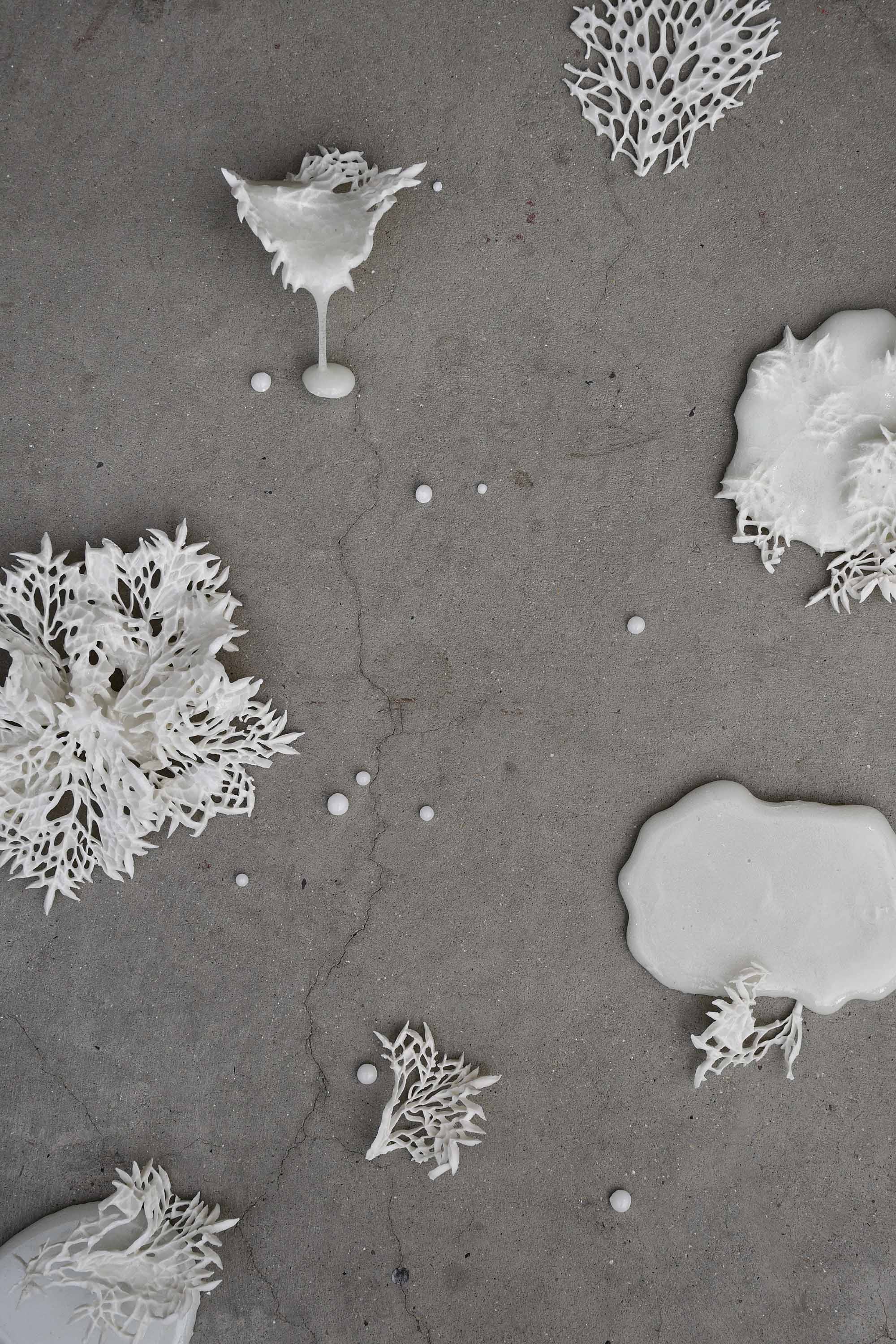 White clay in naturalistic forms with glazed droplets, lying on floor