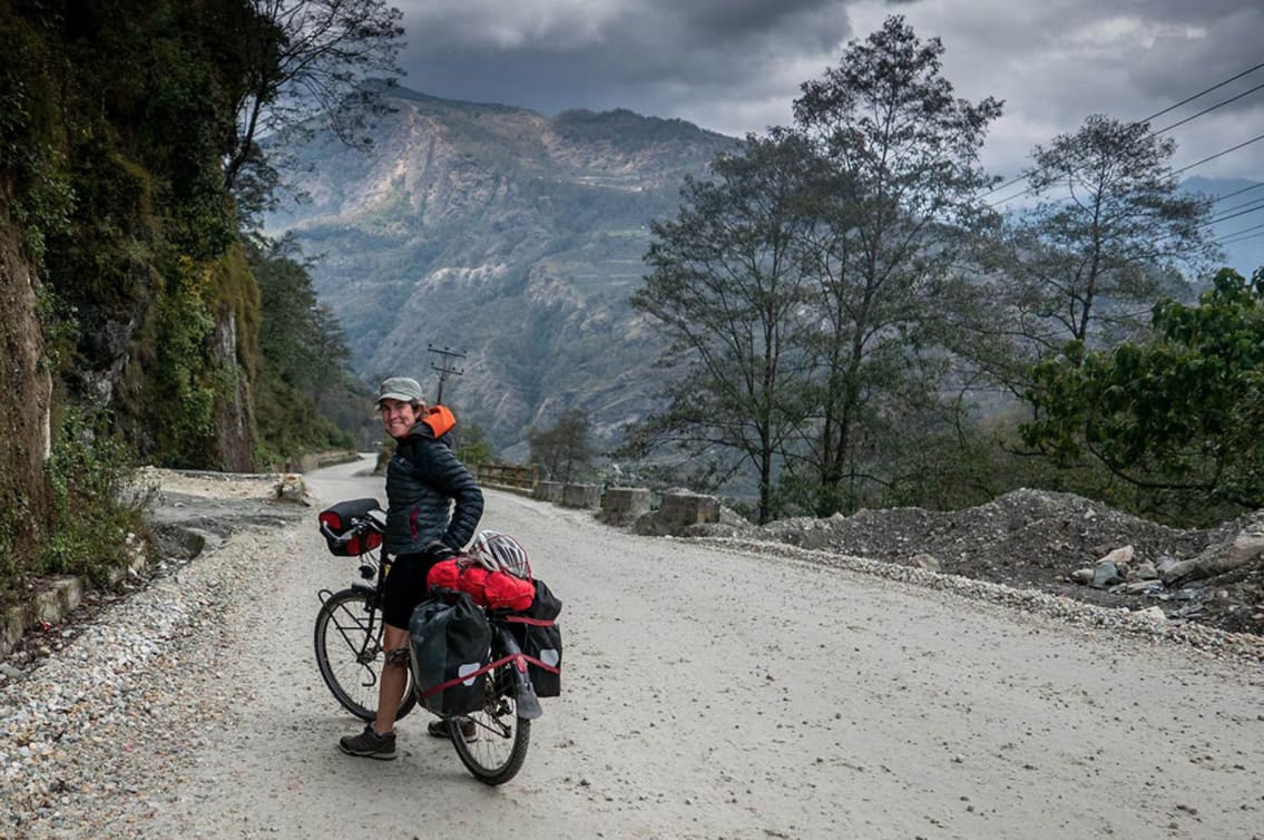 Person on bicycle on road with mountain in background