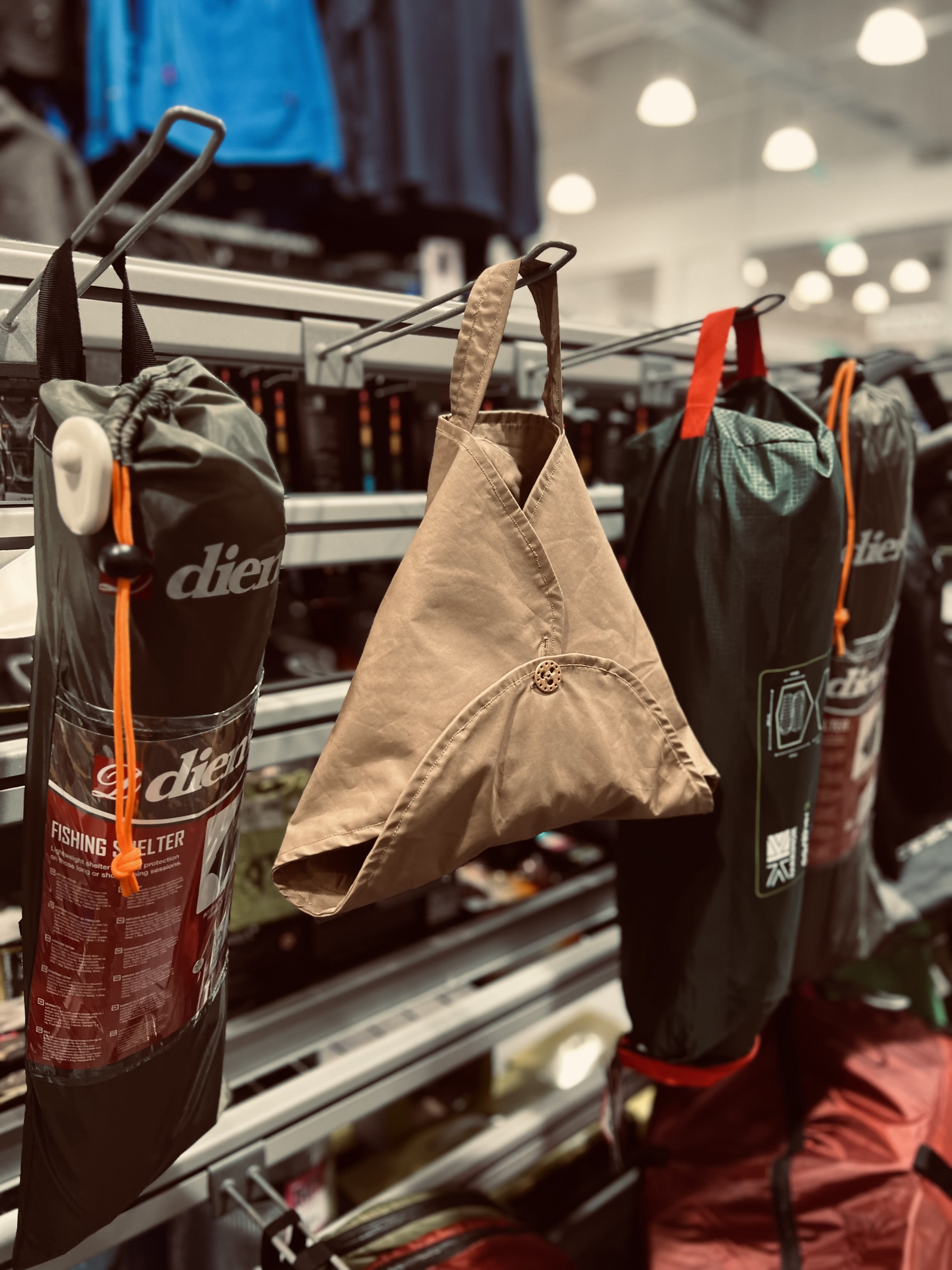 A triangular canvas bag hanging from a rail with camping items