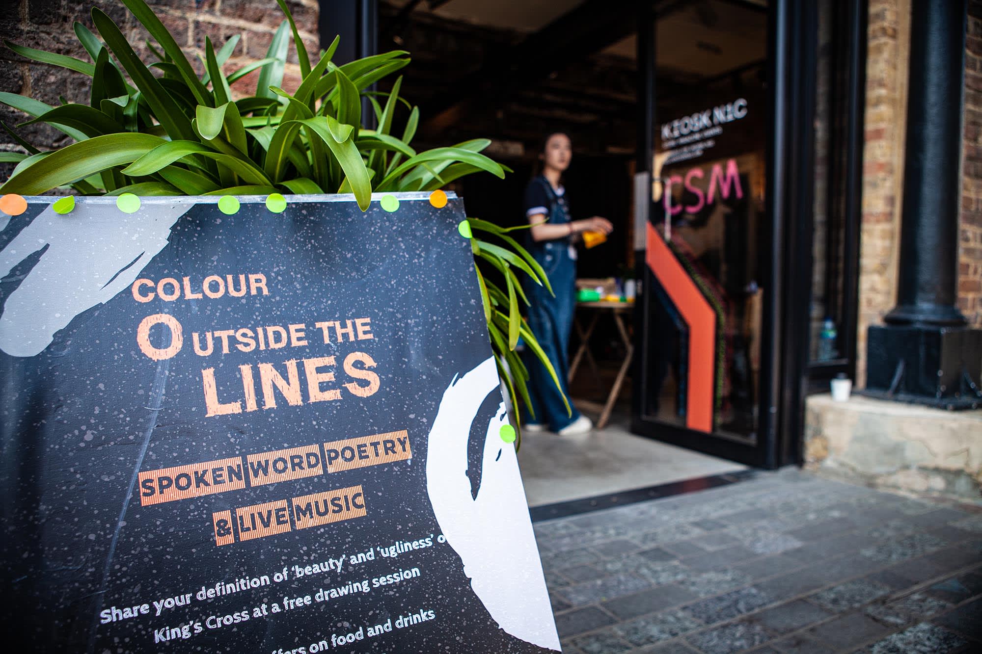 Board declaring 'Colour Outside the Lines' next to open door