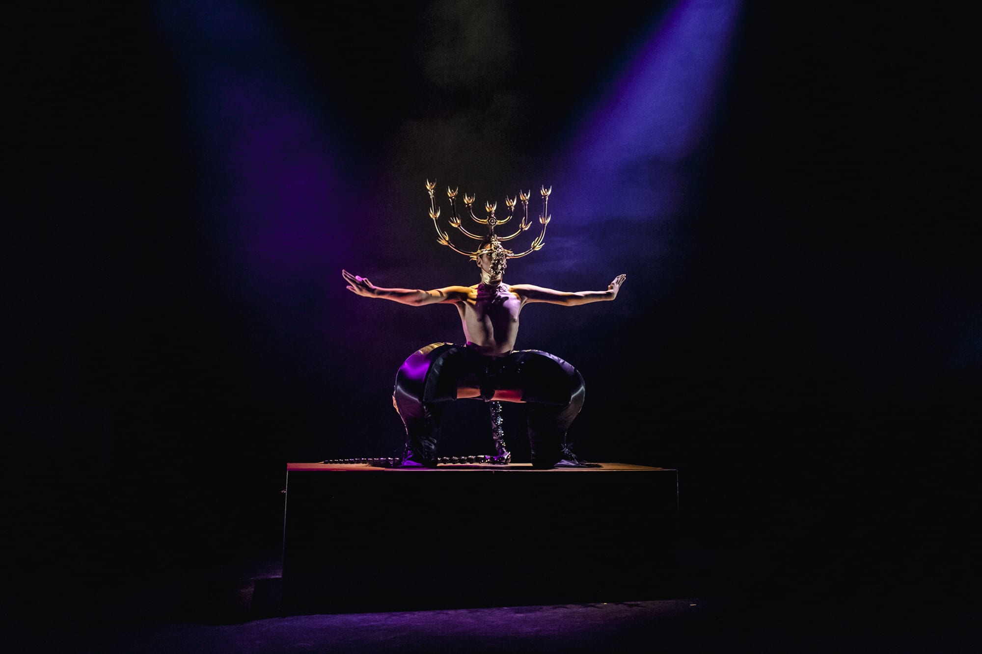 Model with arms spread wearing an extravagant headpiece.