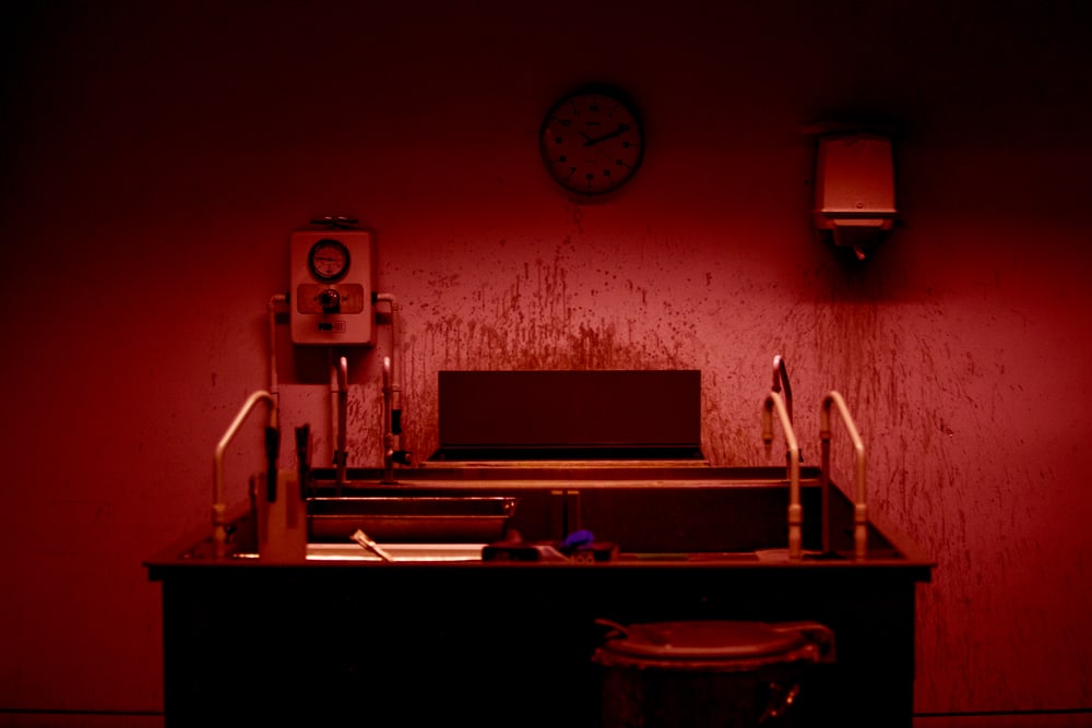 A printing device connected to a meter against a wall that has splashes of ink on it.