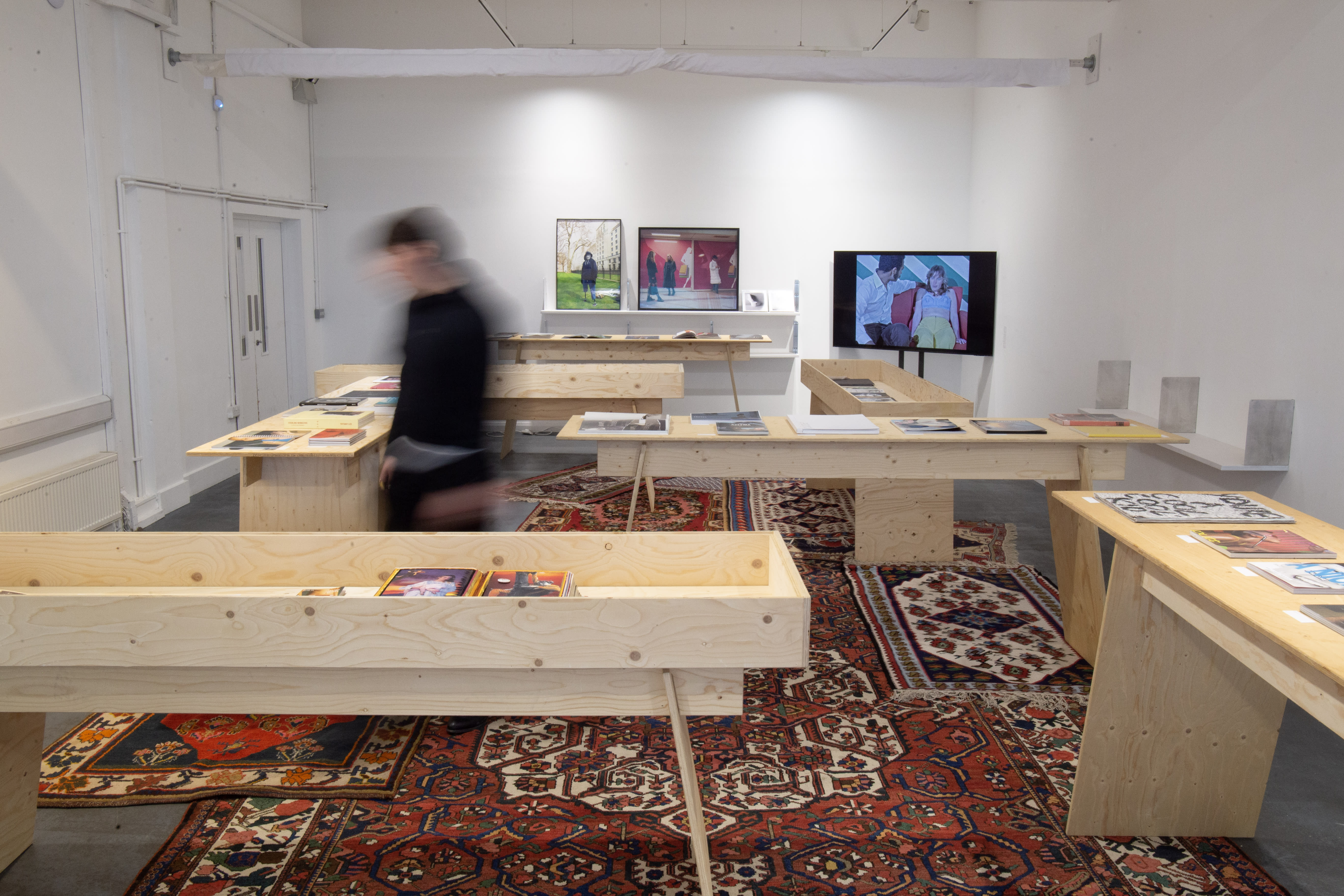 Exhibition space with vitrines, posters and rugs.