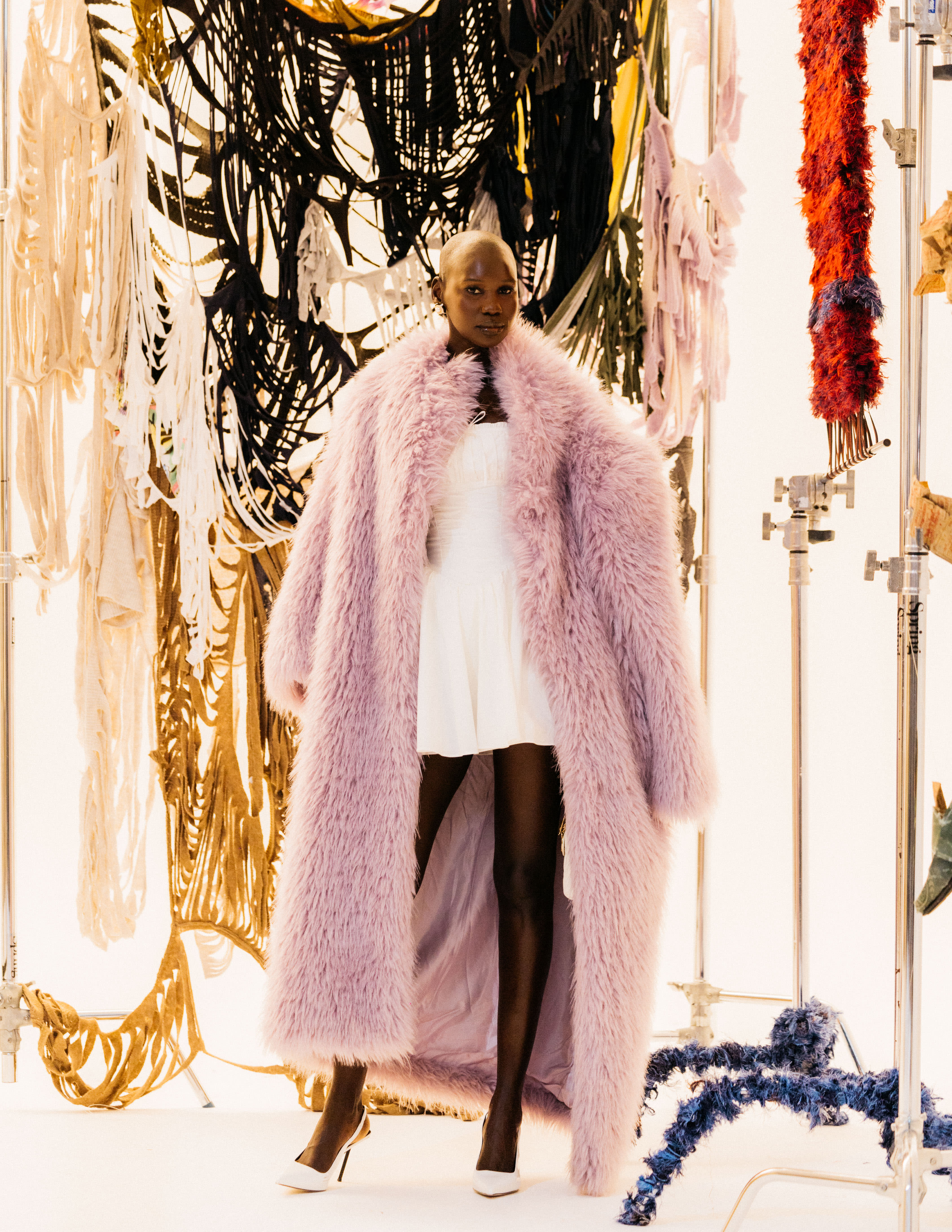 A tall black model in front of a piece of woven art
