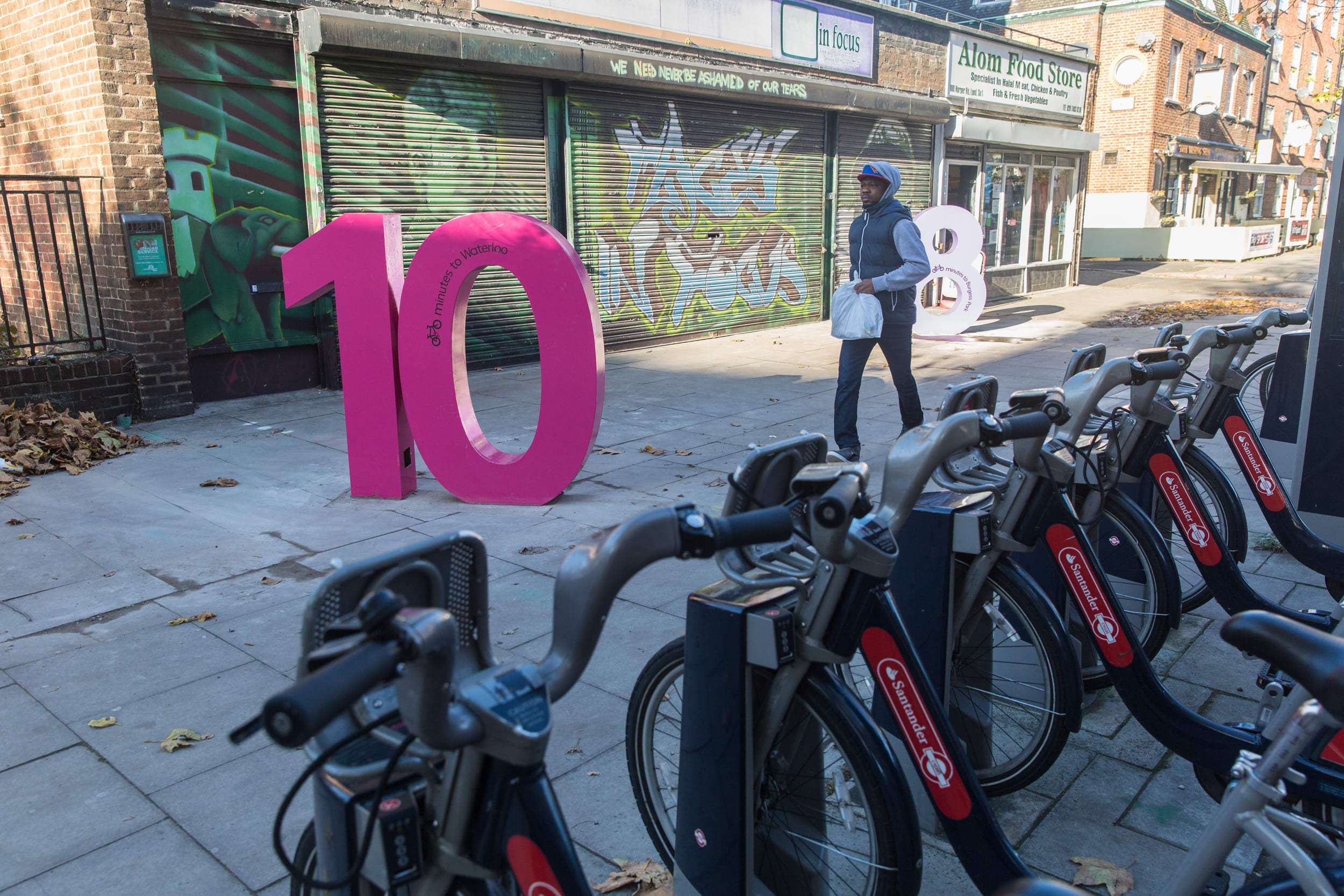 Large colourful numbers standing on a street by a bike hire bay.
