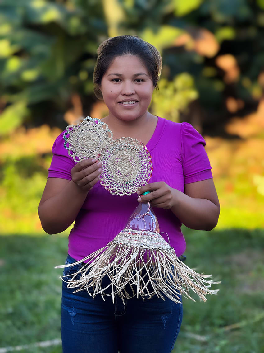 A woman stands holding woven prototype products