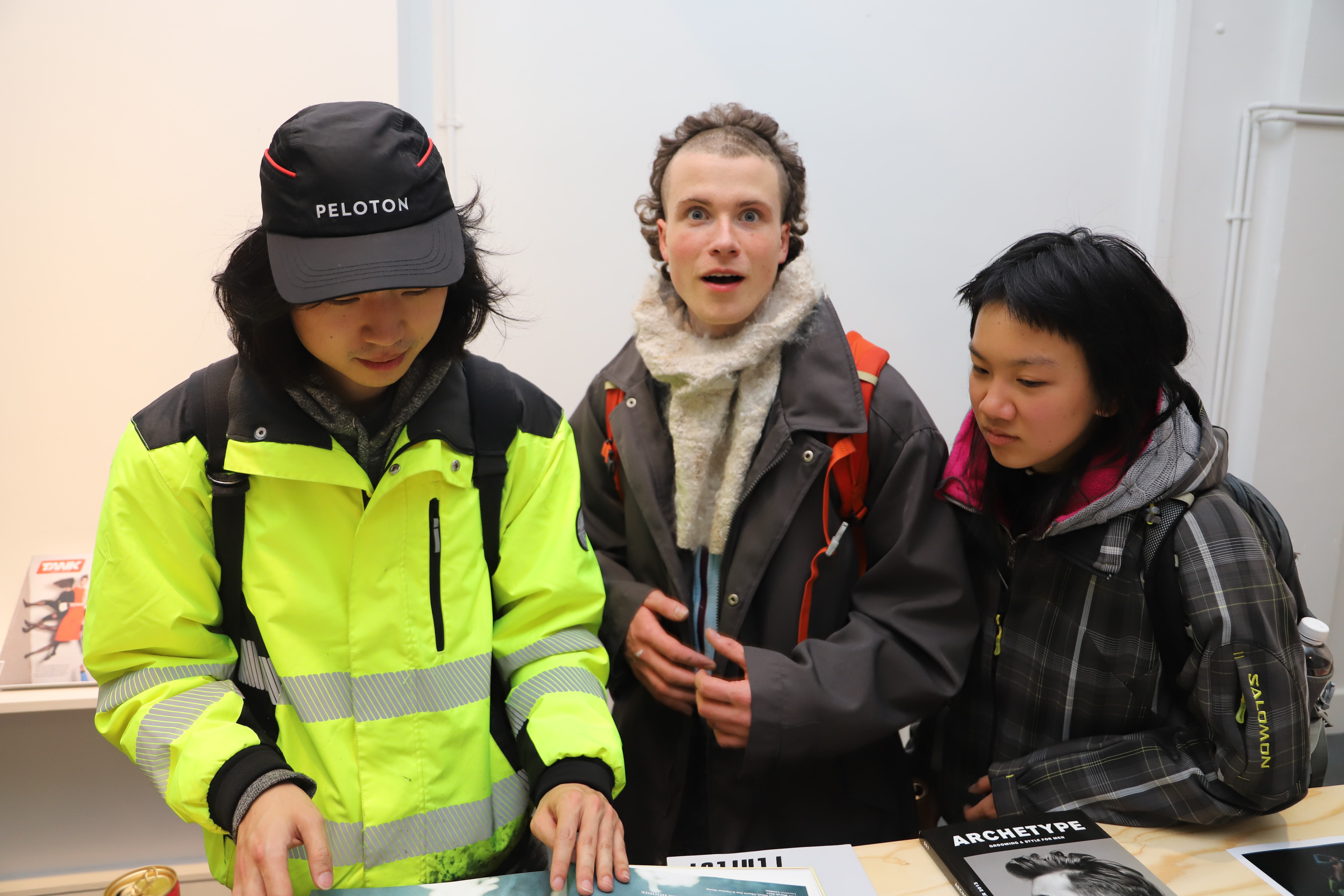 Three students looking through the exhibition magazines.