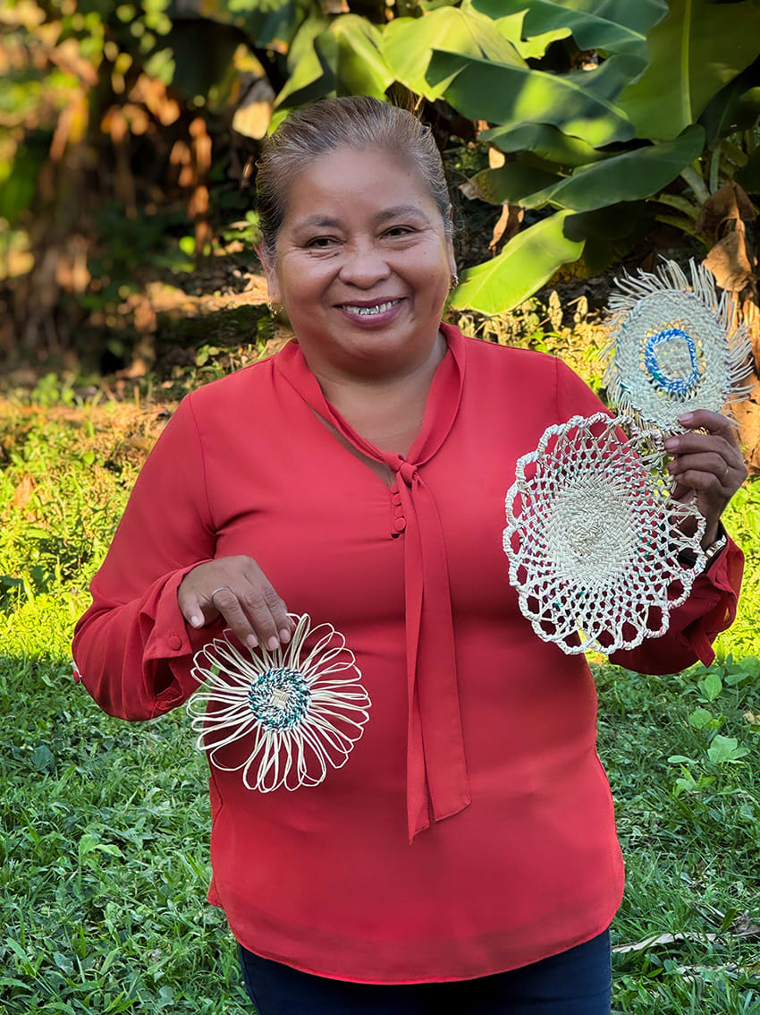 A woman stands holding woven prototypes