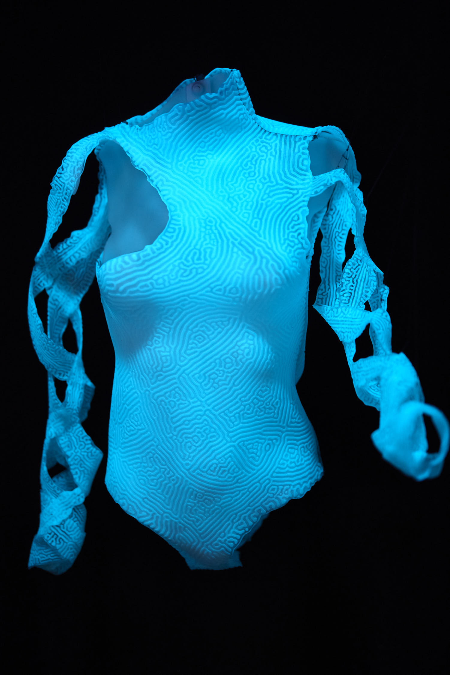 A glowing blue lit swimsuit suspended against a black background