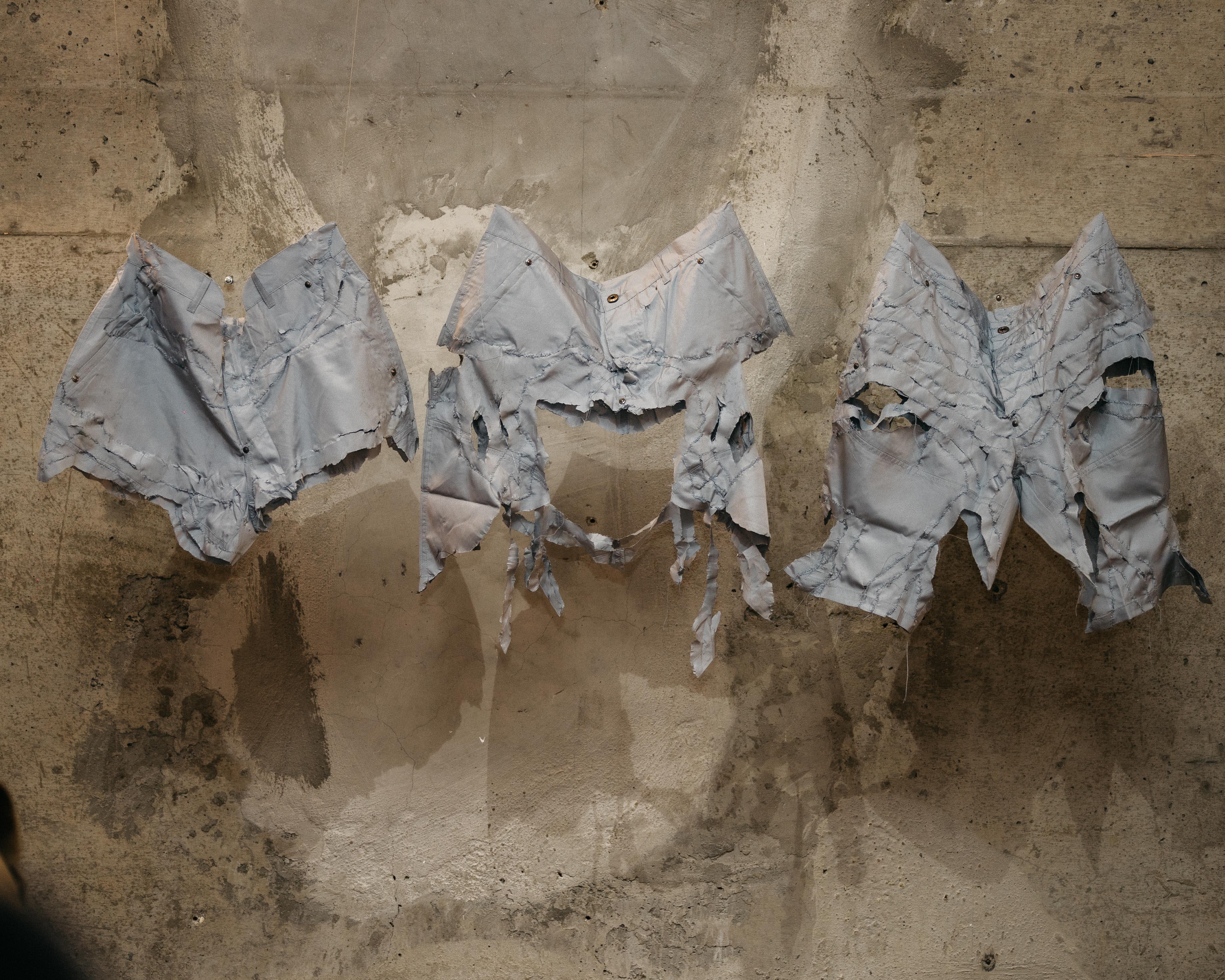 Three distressed jean shorts woven together against a stone background