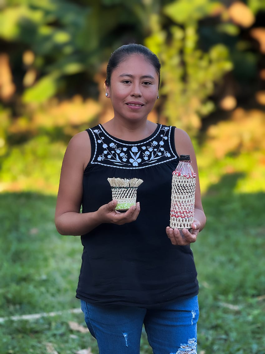A woman stands holding woven prototypes