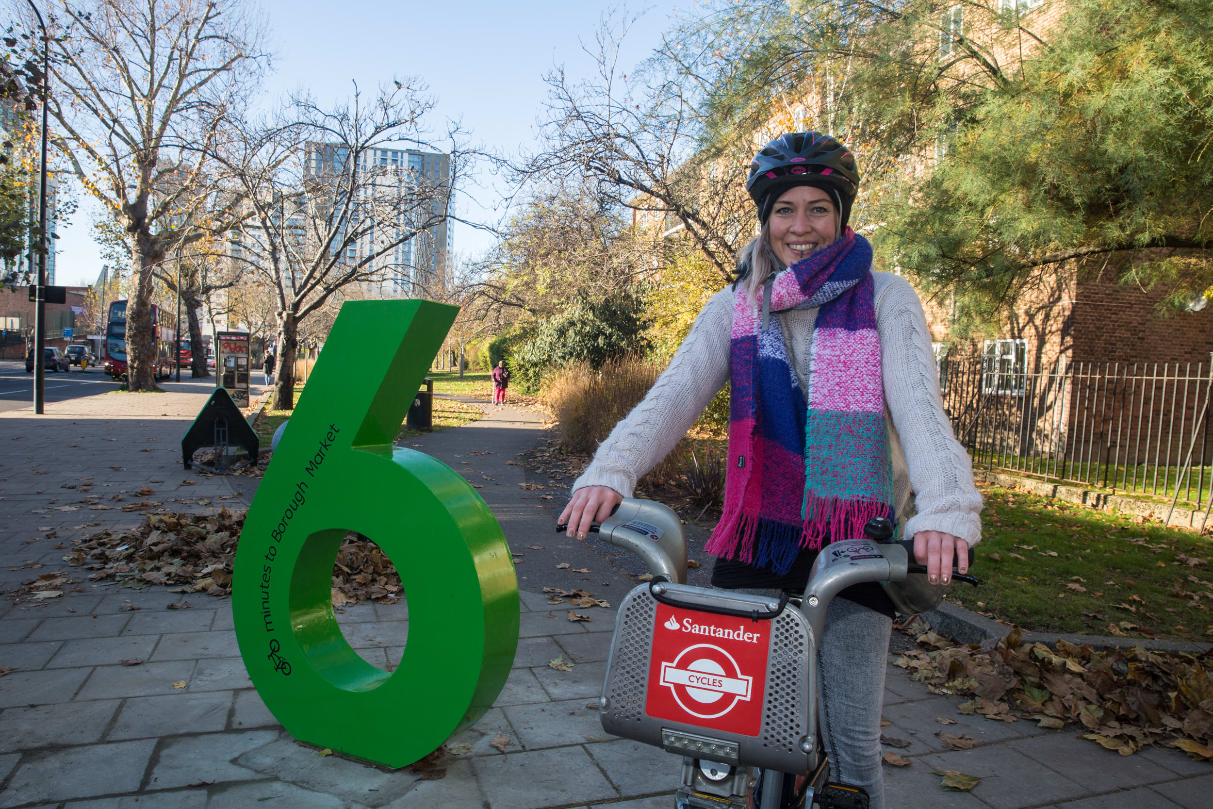Large colourful numbers standing on a street by a bike hire bay.
