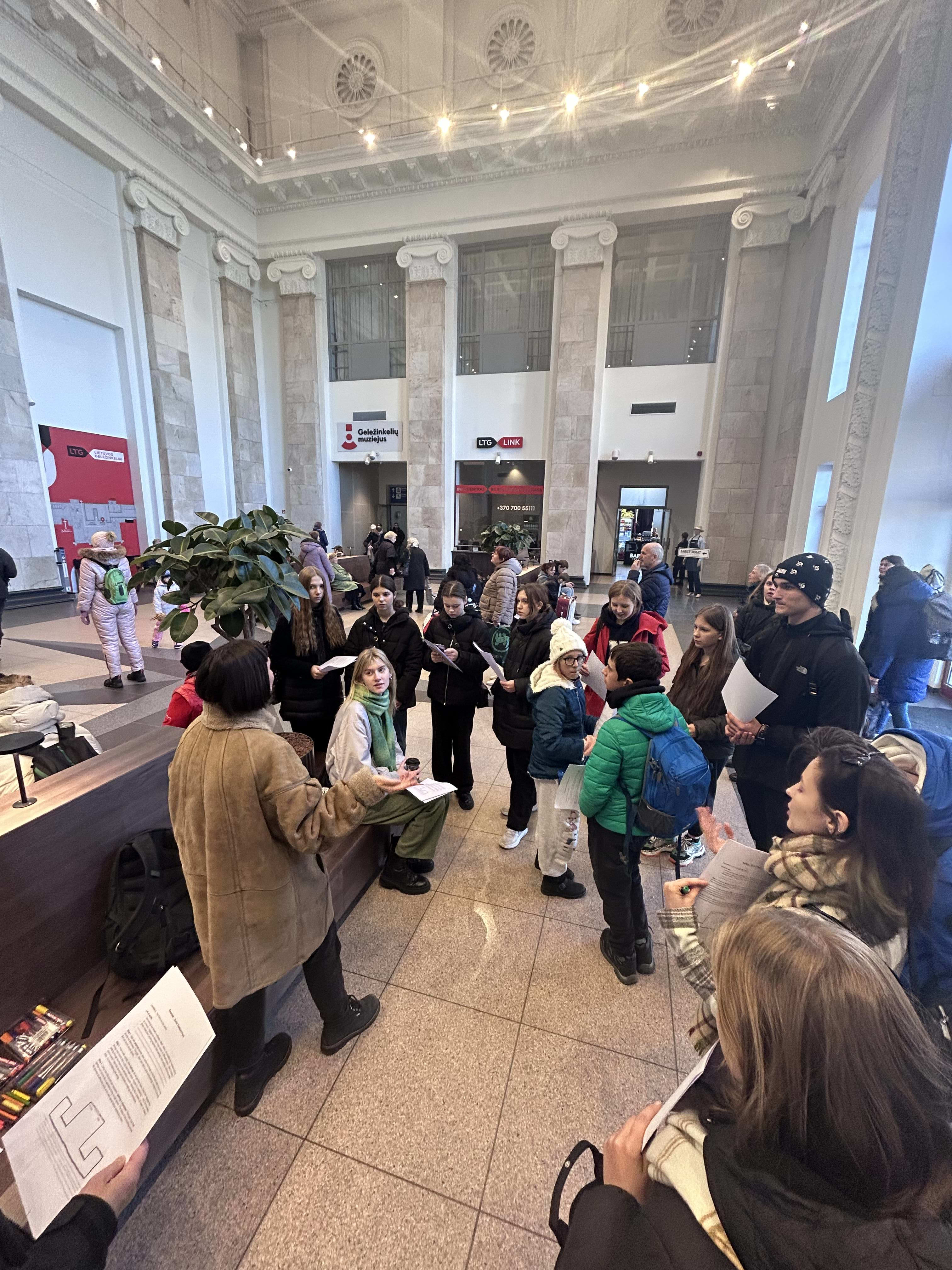 Project participants inside a railway station with ornate decorative features and lighting
