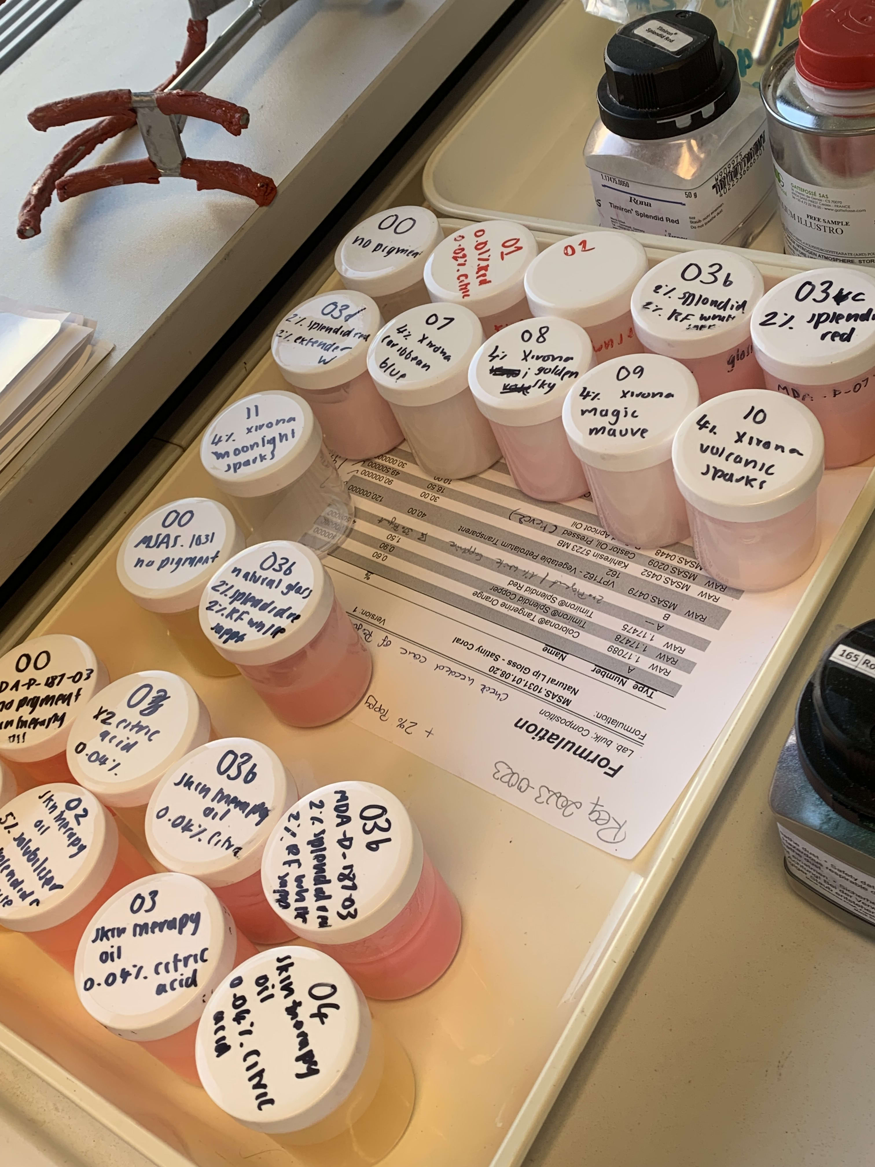 A series of pots from the lab on a tray, holding different formulations.