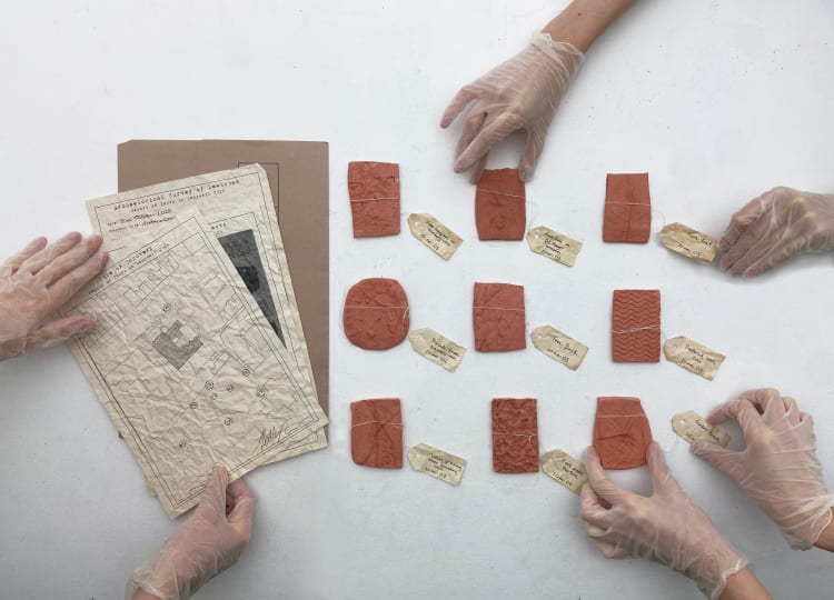 An image of an overlay of 3 pieces of paper and 9 objects with tags on them. The paper and objects are being handled by 3 pairs of hands wearing transparent medical gloves