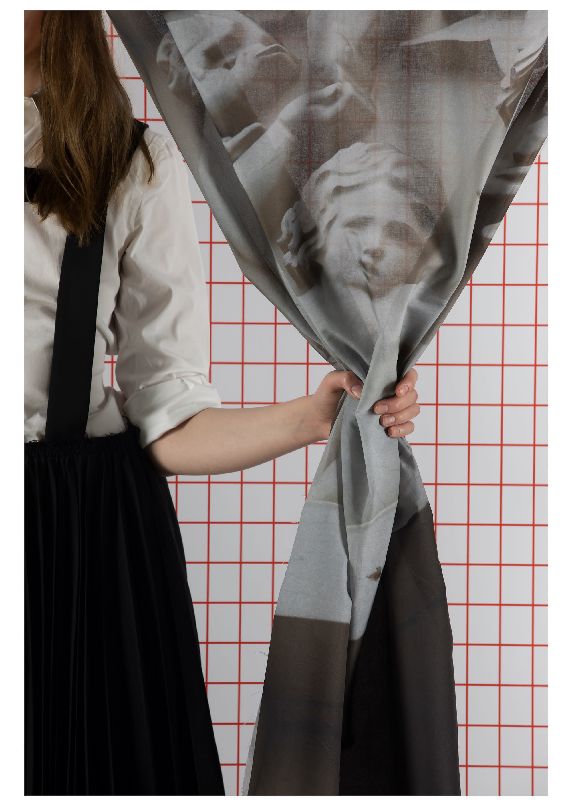 A person holding a piece of material hung like a curtain 