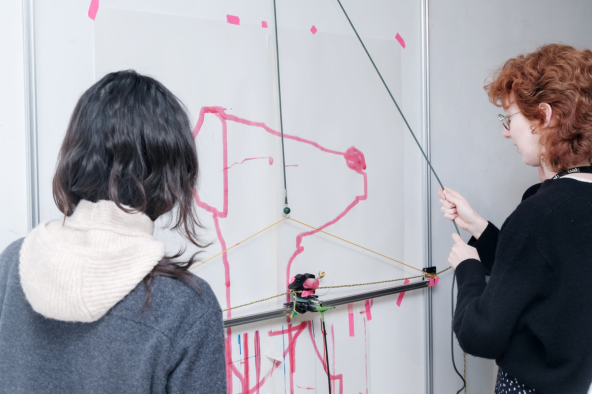 Students using a drawing machine to create an illustration of a dog.