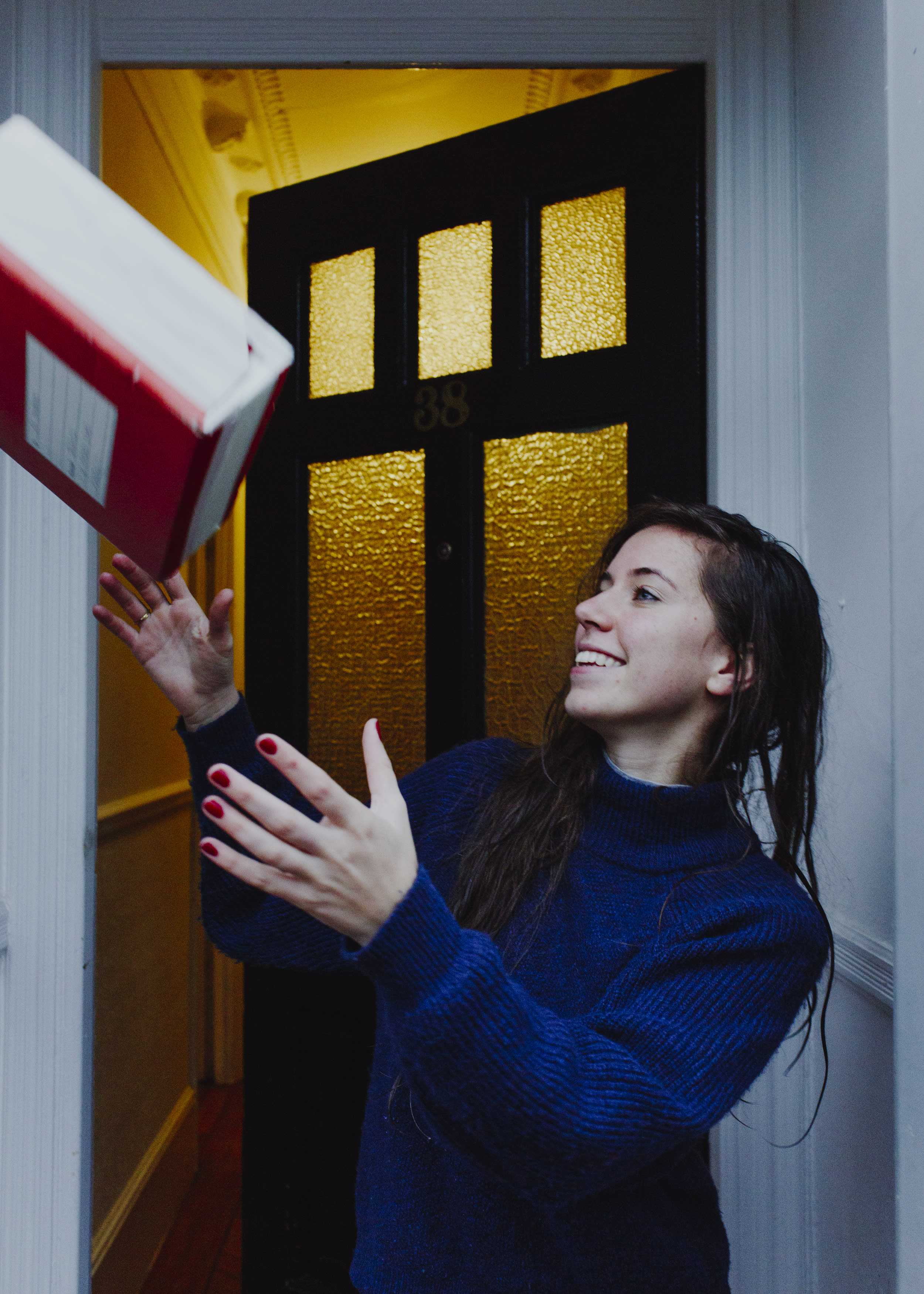 A person at their door ready to catch a package that's mid air.