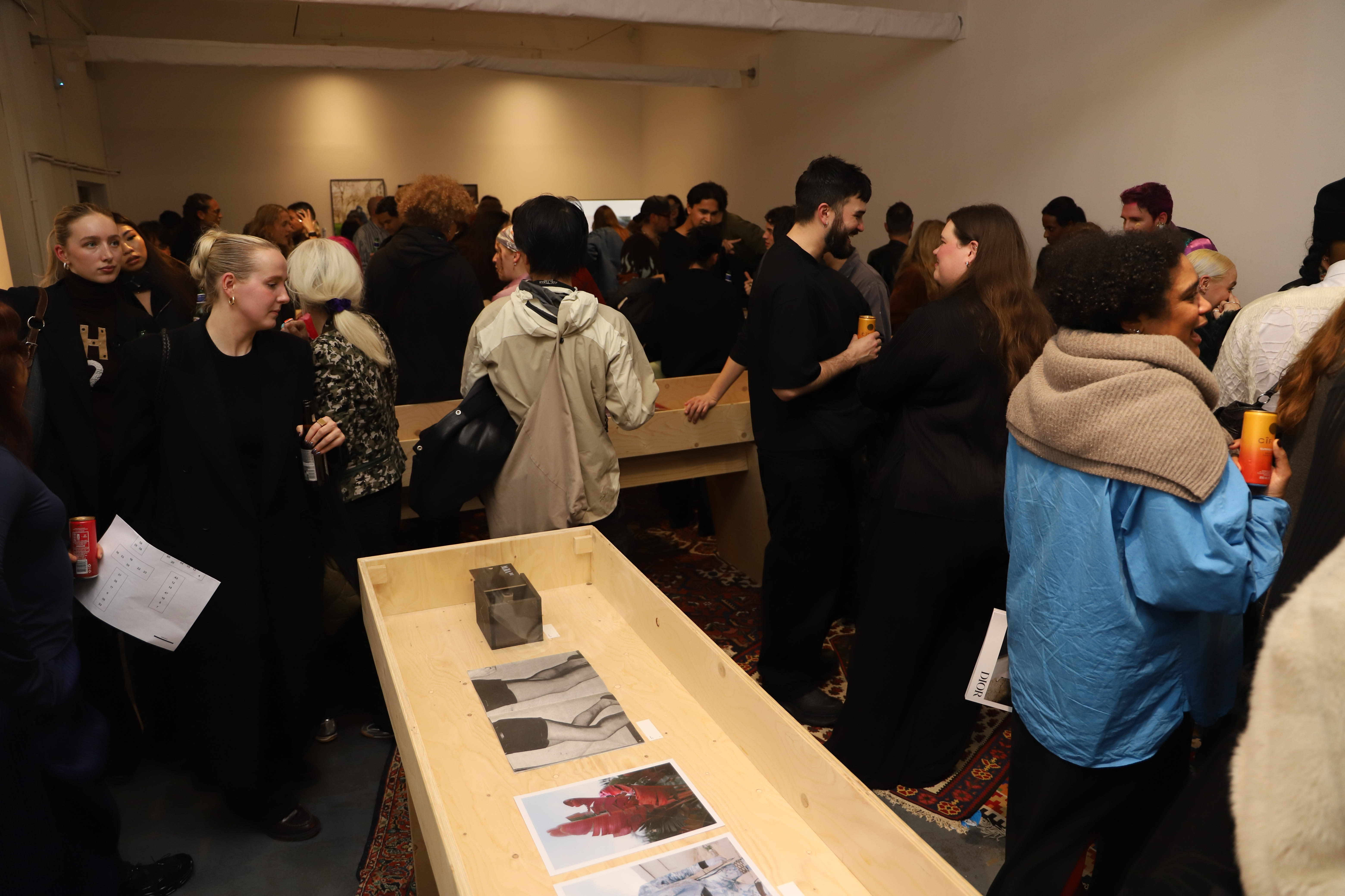 Event guests standing among wooden vitrines with magazines.